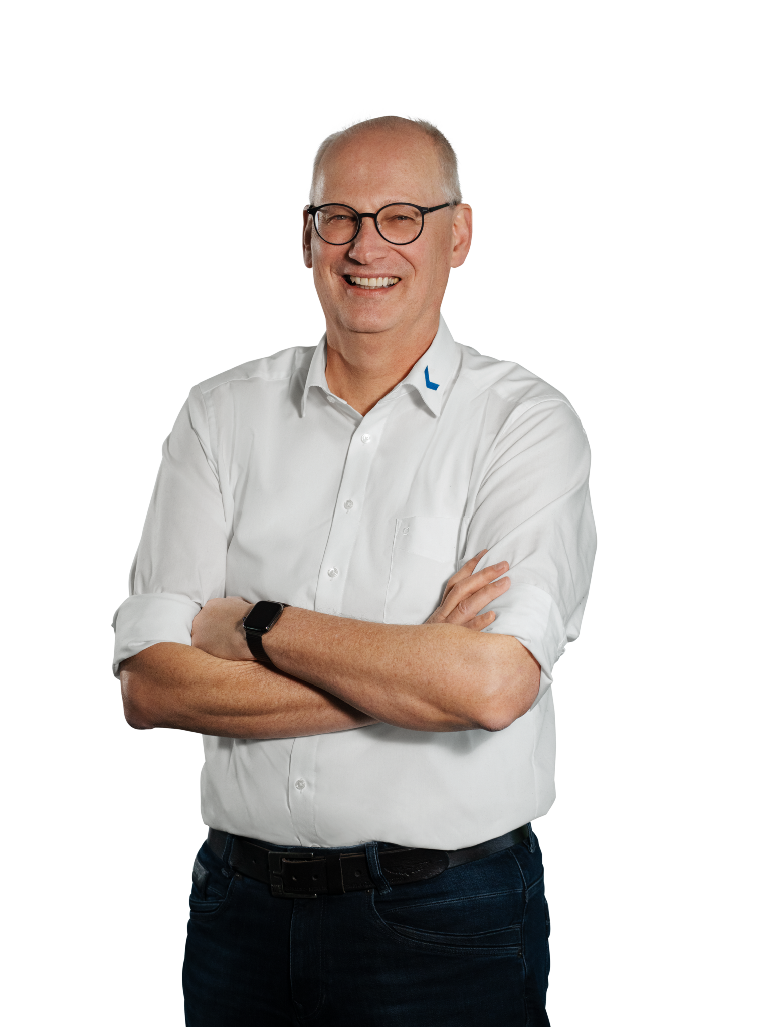 Mann in weißem Hemd mit verschränkten Armen und Brille lächelt.