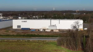 Aerial view of the large production hall at HMT Industries GmbH & Co. KG in Rhede. The B67 federal highway is visible in the foreground.